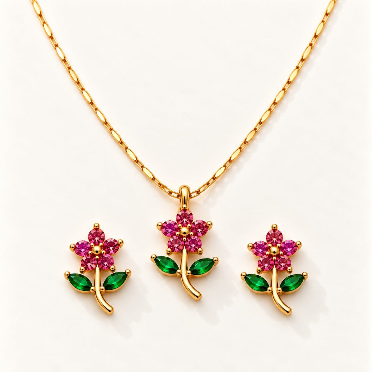 Ruby Rose Set by NuNu: a pink-red rose pendant on a green stem with matching studs, gold tone