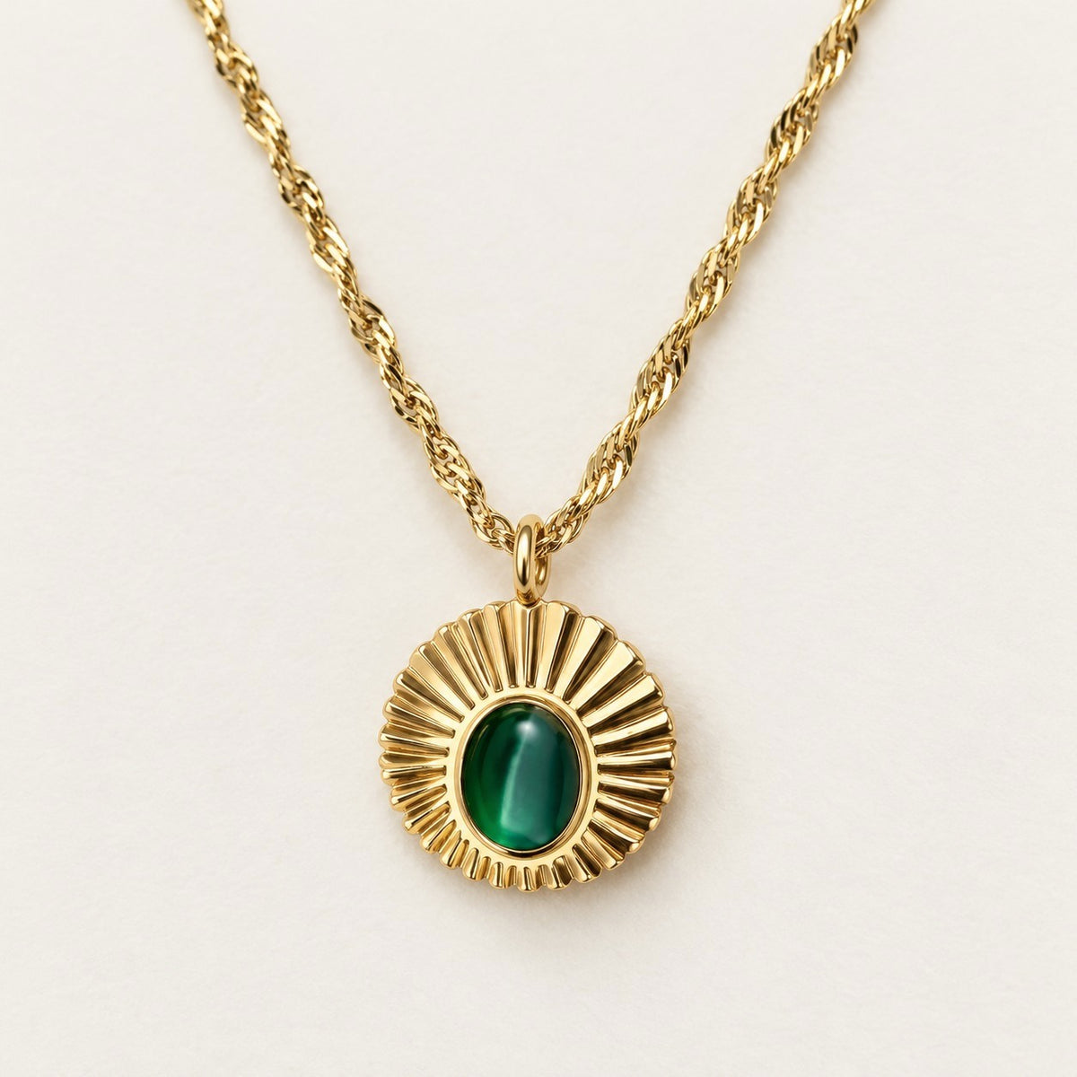 Emerald Sunray Disc Necklace on a cream background