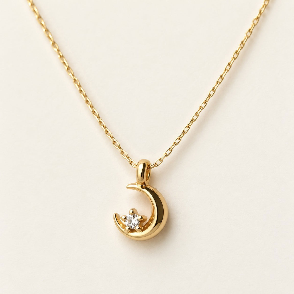 Tiny Crescent Moon Necklace on a cream background